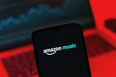 Prag, Çek Cumhuriyeti - 08 12 2025: Dizüstü bilgisayarın önünde duran bir cep telefonu Amazon Müzik logosunu gösteriyor. Amazon Müzik müzik müzik için bir platformdur..
