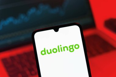Prag, Çek Cumhuriyeti - 08 12 2025: Bir dizüstü bilgisayarın önünde duran bir cep telefonu Duolingo logosunu gösteriyor. Duolingo interaktif olarak dil öğrenmek için bir platformdur..