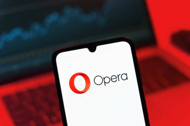 Prag, Çek Cumhuriyeti - 08 12 2025: Dizüstü bilgisayarın önünde duran bir cep telefonu Opera logosunu gösteriyor. Opera hızlı ve güvenli internet taraması için bir web tarayıcısıdır.