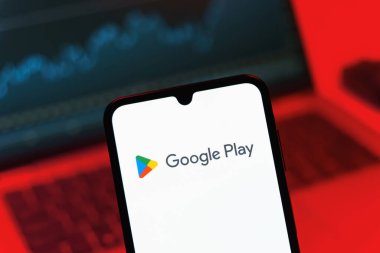 Prag, Çek Cumhuriyeti - 08 12 2025: Bir dizüstü bilgisayarın önünde duran bir cep telefonu Google Play logosunu gösteriyor. Google Play uygulamaları, oyunları ve dijital içeriği indirmek için bir platformdur.