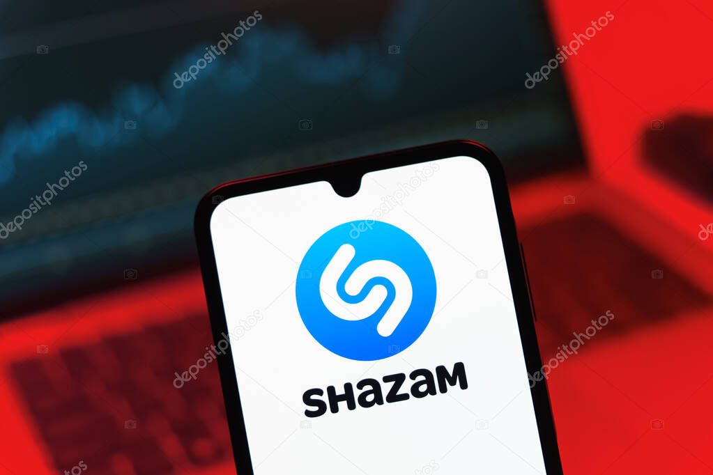 Prague, Czechia - 08 12 2025: A mobile phone standing in front of a laptop displays the Shazam logo. Shazam is an app for identifying songs and music tracks.