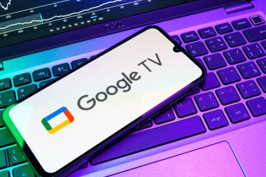Prag, Çek Cumhuriyeti - 08 18 2025: Bir klavyede bir cep telefonu Google TV logosu görüntüler. Google TV film, program ve uygulamalar için bir platformdur..