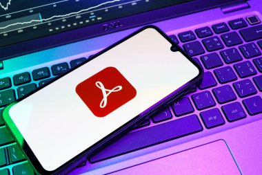 Prag, Çek Cumhuriyeti - 08 18 2025: Klavyede bir cep telefonu Acrobat Reader logosu sergiler. Acrobat Reader, PDF belgelerini görüntülemek ve yönetmek için bir platformdur.