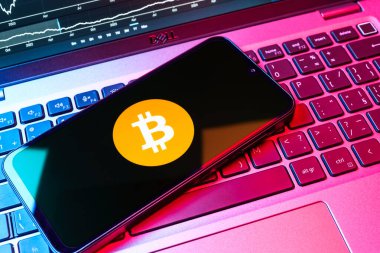 Prag, Çek Cumhuriyeti - 08 18 2025: Klavyede bir cep telefonu Bitcoin logosu sergiler. Bitcoin merkezi olmayan işlemler için dijital bir kripto para birimidir.