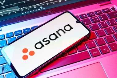 Prag, Çek Cumhuriyeti - 08 18 2025: Klavyede bir cep telefonu Asana logosu sergiler. Asana görev yönetimi ve takım işbirliği için bir platformdur..