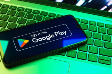 Prag, Çek Cumhuriyeti - 08 01 2025: Dizüstü bilgisayarda bulunan bir cep telefonu Google Play logosunu görüntüler. Google Play uygulamaları, oyunları ve dijital içeriği indirmek için bir platformdur.