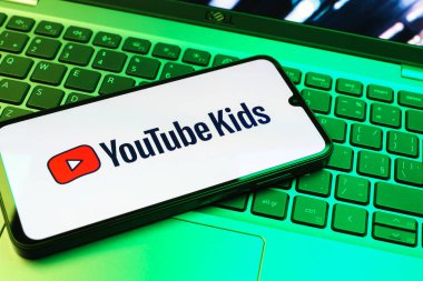 Prag, Çek Cumhuriyeti - 08 01 2025: Laptop klavyesinde duran bir cep telefonu Youtube Kids logosunu gösteriyor. Youtube Kids çocuk dostu video içeriği için bir platformdur.