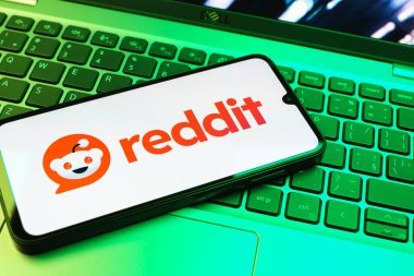 Prag, Çek Cumhuriyeti - 08 01 2025: Dizüstü bilgisayarın üzerinde duran bir cep telefonu Reddit logosunu gösterir. Reddit tartışma, haber ve toplum içeriği için bir platformdur.