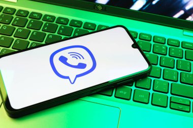 Prag, Çek Cumhuriyeti - 08 01 2025: Dizüstü bilgisayarın üzerinde duran bir cep telefonu Viber logosunu gösteriyor. Viber aramalar, mesajlar ve medya paylaşımı için bir mesajlaşma uygulamasıdır.