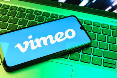 Prag, Çek Cumhuriyeti - 08 01 2025: Dizüstü bilgisayarın üzerinde duran bir cep telefonu Vimeo logosunu gösterir. Vimeo, yüksek kaliteli video sunucu ve paylaşımı için bir platformdur.