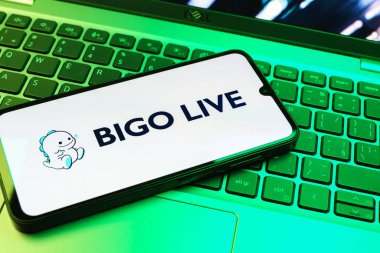Prag, Çek Cumhuriyeti - 08 01 2025: Dizüstü bilgisayarın üzerinde duran bir cep telefonu Bigo Live logosunu gösteriyor. Bigo Live canlı yayın ve sosyal etkileşim için bir platformdur.