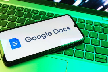 Prag, Çek Cumhuriyeti - 08 01 2025: Dizüstü bilgisayarda bulunan bir cep telefonu Google Docs logosunu görüntüler. Google Docs metin belgeleri oluşturmak ve düzenlemek için bir platformdur.