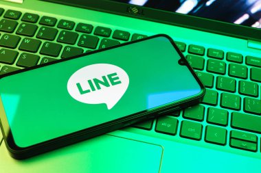 Prag, Çek Cumhuriyeti - 08 01 2025: Dizüstü bilgisayarın üzerinde duran bir cep telefonu Hat logosunu gösterir. Line aramalar, mesajlar ve çokluortam paylaşımı için bir mesajlaşma uygulamasıdır.