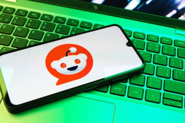 Prag, Çek Cumhuriyeti - 08 01 2025: Dizüstü bilgisayarın üzerinde duran bir cep telefonu Reddit logosunu gösterir. Reddit tartışma, haber ve toplum içeriği için bir platformdur.
