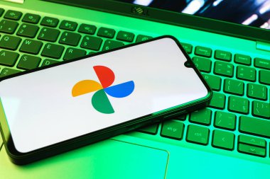 Prag, Çek Cumhuriyeti - 08 01 2025: Laptop klavyesinde duran bir cep telefonu Google Photos logosunu görüntüler. Google Fotoğrafları fotoğraf ve videoları saklamak ve düzenlemek için bir platformdur.