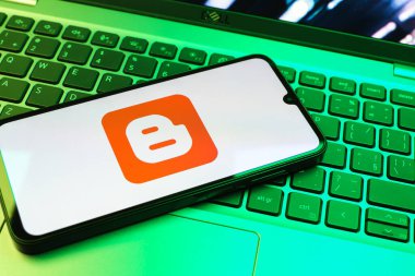 Prag, Çek Cumhuriyeti - 08 01 2025: Dizüstü bilgisayarın üzerinde duran bir cep telefonu Blogger logosunu gösterir. Blogger blog oluşturma ve yayınlama için bir platformdur.