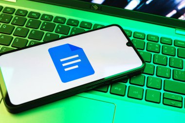 Prag, Çek Cumhuriyeti - 08 01 2025: Dizüstü bilgisayarda bulunan bir cep telefonu Google Docs logosunu görüntüler. Google Docs metin belgeleri oluşturmak ve düzenlemek için bir platformdur.