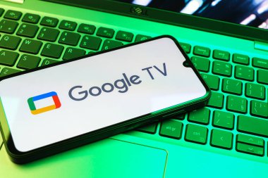 Prag, Çek Cumhuriyeti - 08 01 2025: Laptop klavyesinde uzanan bir cep telefonu Google TV logosunu gösteriyor. Google TV film, program ve uygulamalar için bir platformdur..