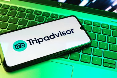 Prag, Çek Cumhuriyeti - 08 01 2025: Dizüstü bilgisayarın üzerinde bulunan bir cep telefonu TripDanışman logosunu gösteriyor. Seyahat danışmanı seyahat değerlendirmeleri, rezervasyonlar ve tavsiyeler için bir platformdur..