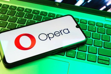 Prag, Çek Cumhuriyeti - 08 01 2025: Dizüstü bilgisayarın üzerinde duran bir cep telefonu Opera logosunu gösteriyor. Opera hızlı ve güvenli internet taraması için bir web tarayıcısıdır.