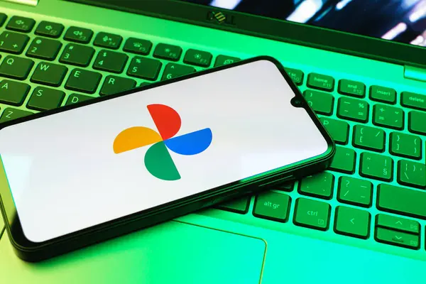 Prag, Çek Cumhuriyeti - 08 01 2025: Laptop klavyesinde duran bir cep telefonu Google Photos logosunu görüntüler. Google Fotoğrafları fotoğraf ve videoları saklamak ve düzenlemek için bir platformdur.