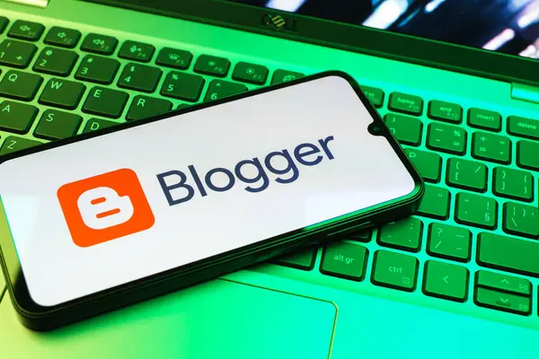 Prag, Çek Cumhuriyeti - 08 01 2025: Dizüstü bilgisayarın üzerinde duran bir cep telefonu Blogger logosunu gösterir. Blogger blog oluşturma ve yayınlama için bir platformdur.