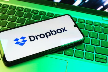 Prag, Çek Cumhuriyeti - 08 01 2025: Laptop klavyesinde duran bir cep telefonu Dropbox logosunu gösterir. Dropbox bulut depolama ve dosya paylaşımı için bir platformdur.