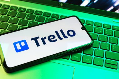 Prag, Çek Cumhuriyeti - 08 01 2025: Dizüstü bilgisayarın üzerinde duran bir cep telefonu Trello logosunu gösterir. Trello, tahta ve görevleri kullanarak proje yönetimi için bir platformdur.