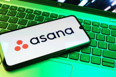 Prag, Çek Cumhuriyeti - 08 01 2025: Dizüstü bilgisayarın üzerinde duran bir cep telefonu Asana logosunu gösterir. Asana görev yönetimi ve takım işbirliği için bir platformdur..