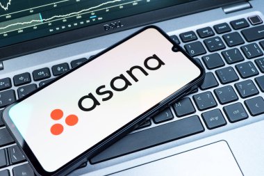 Prag, Çek Cumhuriyeti - 08 18 2025: Klavyede bir cep telefonu Asana logosu sergiler. Asana görev yönetimi ve takım işbirliği için bir platformdur..