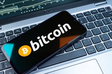 Prag, Çek Cumhuriyeti - 08 18 2025: Klavyede bir cep telefonu Bitcoin logosu sergiler. Bitcoin merkezi olmayan işlemler için dijital bir kripto para birimidir.
