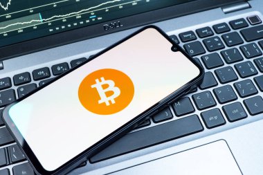 Prag, Çek Cumhuriyeti - 08 18 2025: Klavyede bir cep telefonu Bitcoin logosu sergiler. Bitcoin merkezi olmayan işlemler için dijital bir kripto para birimidir.