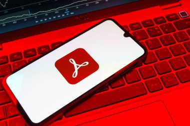 Prag, Çek Cumhuriyeti - 08 18 2025: Klavyede bir cep telefonu Acrobat Reader logosu sergiler. Acrobat Reader, PDF belgelerini görüntülemek ve yönetmek için bir platformdur.