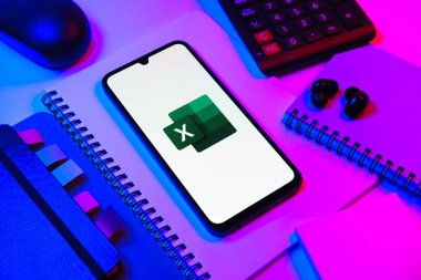 Prag, Çek Cumhuriyeti - 08 18 2025: Excel logosu sergilenen bir cep telefonu ile ofis malzemeleri düzenlemesi. Excel, tablo, veri analizi ve hesaplamalar için bir yazılımdır..