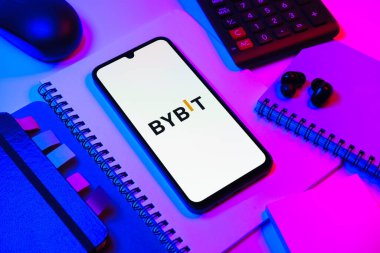 Prag, Çek Cumhuriyeti - 08 18 2025: Merkezde Bybit logosunu gösteren bir cep telefonu ile ofis malzemeleri düzenlemesi. Bybit şifreli para ve türev ticareti için bir platformdur.