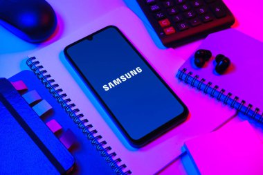 Prag, Çek Cumhuriyeti - 08 18 2025: Merkezde Samsung logosu sergilenen bir cep telefonu ile ofis malzemeleri düzenlemesi. Samsung elektronik ve cihaz üreten bir teknoloji şirketi..