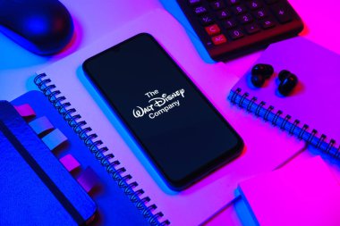 Prag, Çek Cumhuriyeti - 08 18 2025: Merkezde Walt Disney logosunu gösteren bir cep telefonu ile ofis malzemeleri düzenlemesi. Walt Disney film, park ve medya için bir eğlence şirketidir..