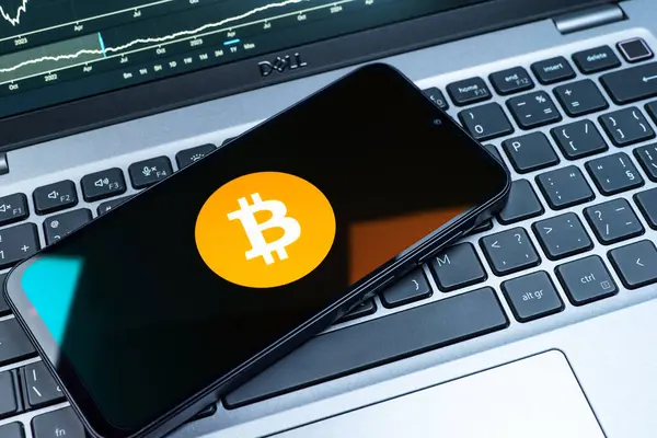 Prag, Çek Cumhuriyeti - 08 18 2025: Klavyede bir cep telefonu Bitcoin logosu sergiler. Bitcoin merkezi olmayan işlemler için dijital bir kripto para birimidir.