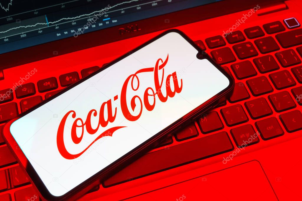 Prague, Czechia - 08 18 2025: A mobile phone on a keyboard displays Coca-Cola logo. Coca-Cola is a beverage company known for its soft drinks.