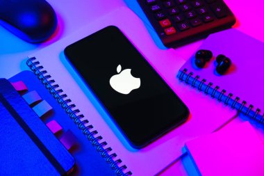 Prag, Çek Cumhuriyeti - 08 18 2025: Merkezi Apple logosunu gösteren bir cep telefonu ile ofis malzemeleri düzenlemesi. Apple iPhone, bilgisayar ve hizmet üreten bir teknoloji şirketidir..