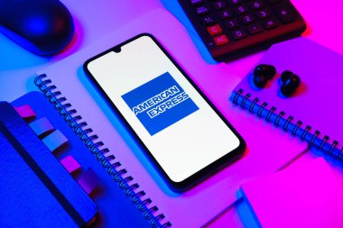 Prag, Çek Cumhuriyeti - 08 18 2025: Merkezde American Express logosunu gösteren bir cep telefonu ile ofis malzemeleri düzenlemesi. American Express kart ve bankacılık sunan bir finans şirketidir..