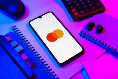 Prag, Çek Cumhuriyeti - 08 18 2025: Merkezde Mastercard logosu sergilenen bir cep telefonu ile ofis malzemeleri düzenlemesi. Mastercard ödeme kartları ve hizmetler sağlayan bir finans şirketidir..