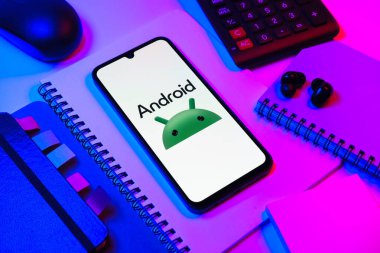 Prag, Çek Cumhuriyeti - 08 18 2025: Merkezde Android logosunu gösteren bir cep telefonu ile ofis malzemeleri düzenlemesi. Android akıllı telefonlar ve tabletler için mobil bir işletim sistemidir..