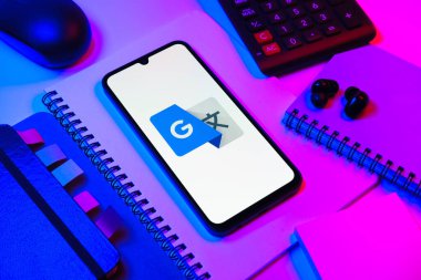 Prag, Çek Cumhuriyeti - 08 18 2025: Merkezde Google Translate logosunu gösteren bir cep telefonu ile ofis malzemeleri düzenlemesi. Google Çevirisi metni ve konuşmayı diller arası çevirmek için bir platformdur..