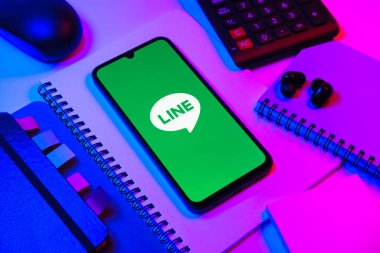 Prag, Çek Cumhuriyeti - 08 18 2025: Merkezinde hat logosu sergilenen bir cep telefonu ile ofis malzemeleri düzenlemesi. Line aramalar, mesajlar ve çokluortam paylaşımı için bir mesajlaşma uygulamasıdır.