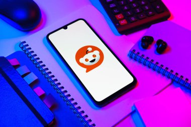 Prag, Çek Cumhuriyeti - 08 18 2025: Merkezde Reddit logosunu gösteren bir cep telefonu ile ofis malzemeleri düzenlemesi. Reddit tartışma, haber ve toplum içeriği için bir platformdur.