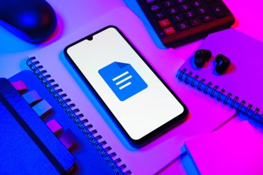 Prag, Çek Cumhuriyeti - 08 18 2025: Merkezde Google Docs logosunu gösteren bir cep telefonu ile ofis malzemeleri düzenlemesi. Google Docs metin belgeleri oluşturmak ve düzenlemek için bir platformdur.