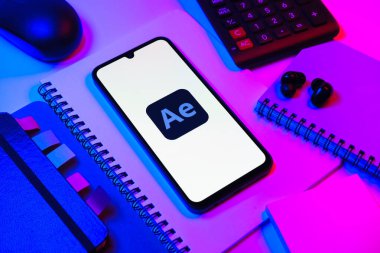 Prag, Çek Cumhuriyeti - 08 18 2025: Ofis malzemelerinin merkezde After Effects logosu sergilenen bir cep telefonu ile düzenlenmesi. After Effects hareket grafikleri ve görsel efektler için bir yazılımdır..