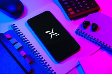 Prag, Çek Cumhuriyeti - 08 18 2025: Merkezinde X logosu sergilenen bir cep telefonu ile ofis malzemeleri düzenlemesi. X, kısa gönderileri ve güncellemeleri paylaşmak için bir platformdur.