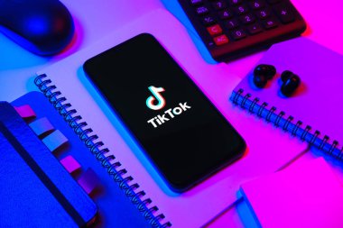 Prag, Çek Cumhuriyeti - 08 18 2025: Merkezde TikTok logosunu gösteren bir cep telefonu ile ofis malzemeleri düzenlemesi. TikTok kısa, yaratıcı ve viral video platformu.
